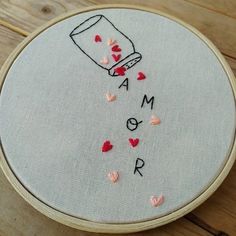 a hand embroidery project on a wooden table with hearts and a jar that says,'i am o r '