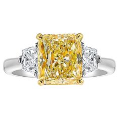 Classic and beautiful three stone ring with a 3ct Fancy Yellow elongated Radiant cut set in Platinum and 18kt Yellow Gold with 0.50ct total weight colorless trapezoids Making Extraordinary Attainable with Rare Colors Elongated Radiant Cut, Radiant Diamond Ring, Elongated Radiant, Radiant Diamond Rings, Rare Colors, Three Stone Ring, Radiant Diamond, Expensive Jewelry, Gemstones Jewelry