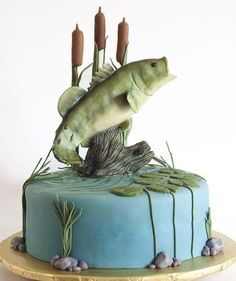 there is a cake decorated with a fish and reeds on the top, as well as candles in the bottom