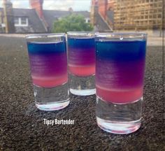 three glasses filled with colored liquid sitting on top of a table next to each other