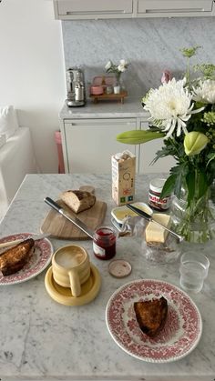 a table topped with plates and cups filled with food next to a vase full of flowers