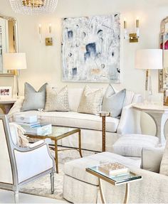 a living room filled with white furniture and lots of pillows on top of couches