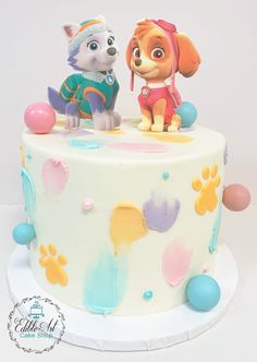 there is a cake with a dog and puppy on it that is decorated in pastel colors