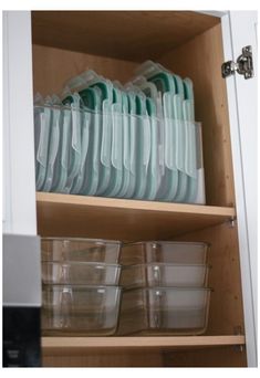 dishes are stacked on top of each other in a cupboard with clear plastic cups and containers