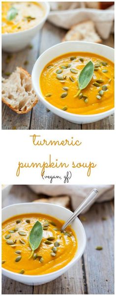 two bowls filled with pumpkin soup on top of a wooden table next to bread slices