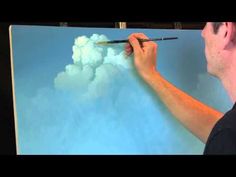 a man is painting clouds on a canvas