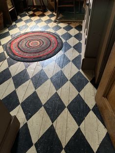 a black and white checkered floor with a red circle rug in the middle on it