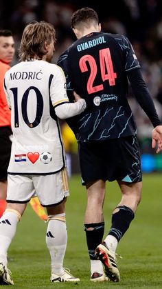 two soccer players standing next to each other on a field