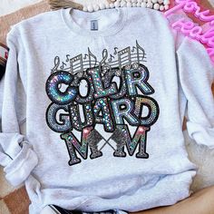 a sweatshirt with the words color guard and music notes on it sitting on a bed