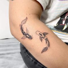 a woman's arm with two koi fish tattoos on it