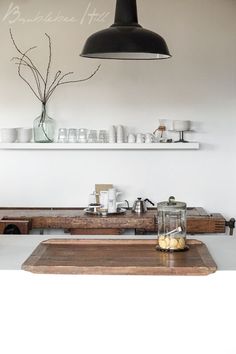 a kitchen with white walls and wooden counter tops, two hanging lights above the stove