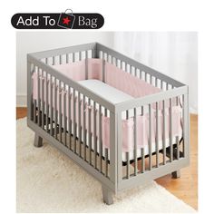 a baby crib with pink bedding and white rugs on top of it