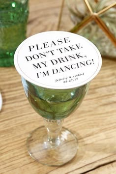 a wine glass with a sign that says please don't take my drink i'm dancing