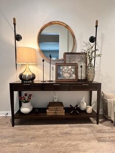 a living room with a couch, table and mirror on the wall next to it