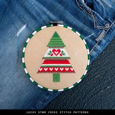 a cross stitch christmas tree ornament on jeans