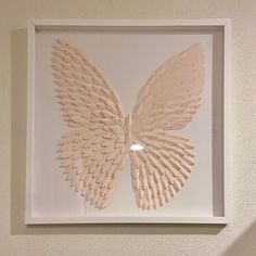 a white framed artwork with a large butterfly on it's back and wings spread out