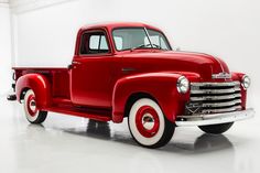 an old red truck parked in a white room