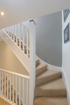 there is a white staircase with beige carpet on the ground and light gray walls in the background