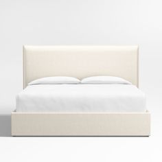 a bed with white sheets and pillows on it