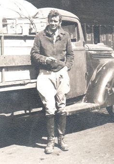 an old black and white photo of a man sitting on the back of a truck