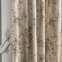 a curtain with floral designs hanging from it's rod ends in front of a mirror