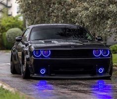 the front end of a black car with blue lights on it's headlight