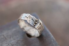 a silver ring sitting on top of a piece of wood with two pearls in it