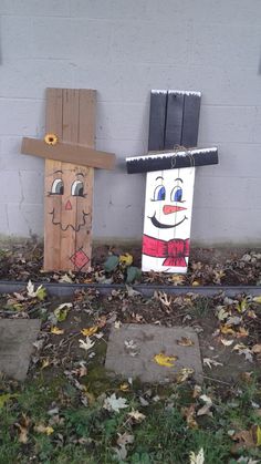 two wooden scarecrows sitting next to each other on the ground in front of a building