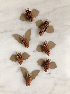 several pieces of paper cut out to look like bats with pine cones on the back