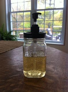 a mason jar filled with liquid sitting on top of a table next to a window