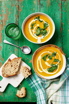 two bowls of soup with bread on a green table