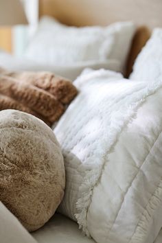 a teddy bear laying on top of a bed next to pillows