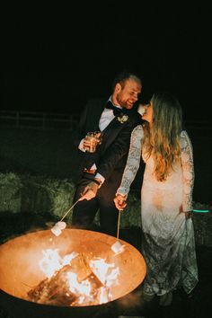 a man and woman standing next to an open fire pit