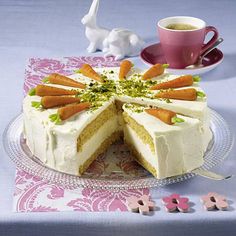 a cake with carrots on it sitting next to a cup and saucer