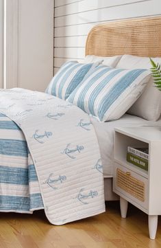 a bed with blue and white striped bedspread next to a nightstand in a bedroom