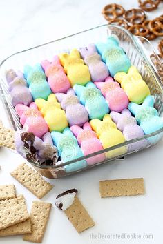 colorful marshmallows and pretzels in a glass dish next to crackers