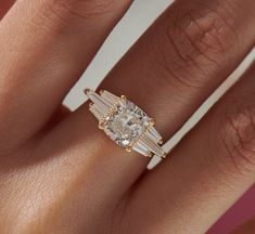 a woman's engagement ring with three baguettes on the band and side stones