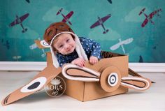 a little boy is sitting in a cardboard box that has an airplane on the side