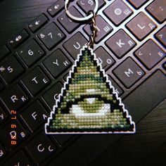 a computer keychain with an eye on it sitting next to a laptop keyboard