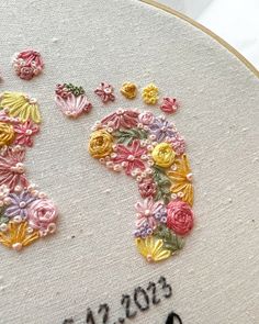 a close up of a cross stitch pattern on a hoop with flowers in the middle