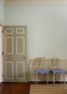 two chairs sitting next to each other on a hard wood floor in front of a door