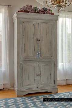 an old white armoire with flowers on top