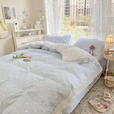 a bed with blue sheets and white polka dots on it in front of a window