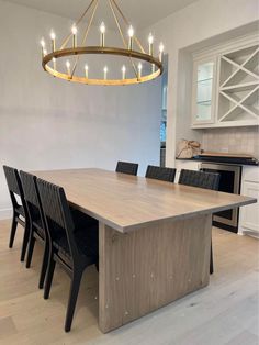 a dining room table with black chairs and a chandelier hanging from the ceiling