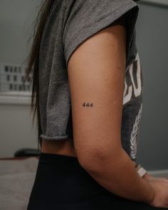 a woman with a small tattoo on her left arm and the number 544 written in cursive writing