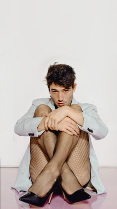 a man sitting on the ground with his legs crossed wearing fishnet stockings and high heels