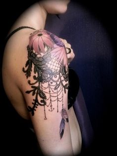 a woman's arm with a tattoo on it that has feathers and beads hanging from it