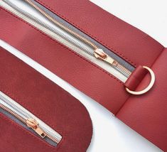 two red purses with gold zippers on the handles and one has a ring at the end