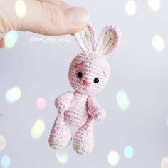 a tiny pink crocheted bunny hanging from a string with bubbles in the background