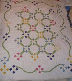 a quilt is laying on top of a bed with white sheets and colorful squares in the middle